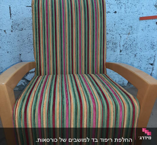 כיסא מרופד בפסים צבעוניים על רקע קיר בטון